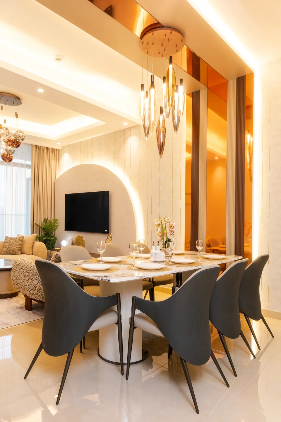 Imperial Avenue Apartment, Downtown Dubai: dining area with dark grey chairs and glass pendants opening onto the living room.