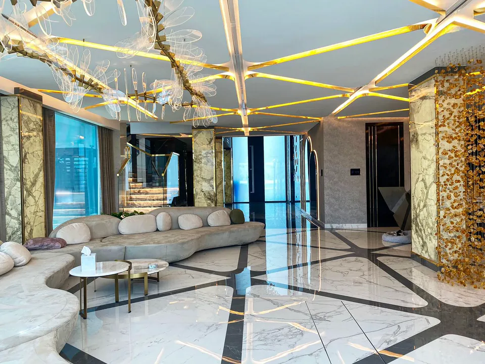 MK Villa, Palm Jumeirah: living area with a curved cream sofa, marble-look floor with dark inlay and a gold-lit ceiling.