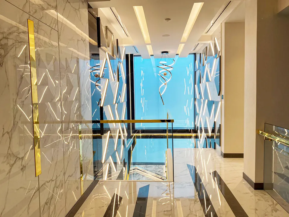 MK Villa, Palm Jumeirah: marble-look hallway with gold trim and white angular wall art beside a tall window.